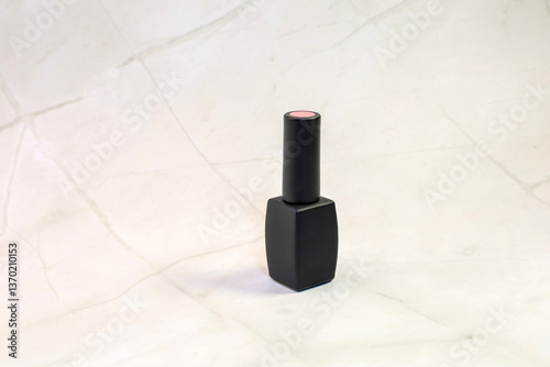 A bottle of pink nail polish is sitting on a clean white surface