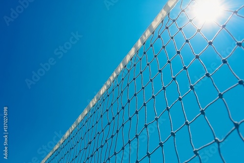 Tennis or volleyball net against clear blue sky background. Outdoors sports field in sunny day. Low angle view