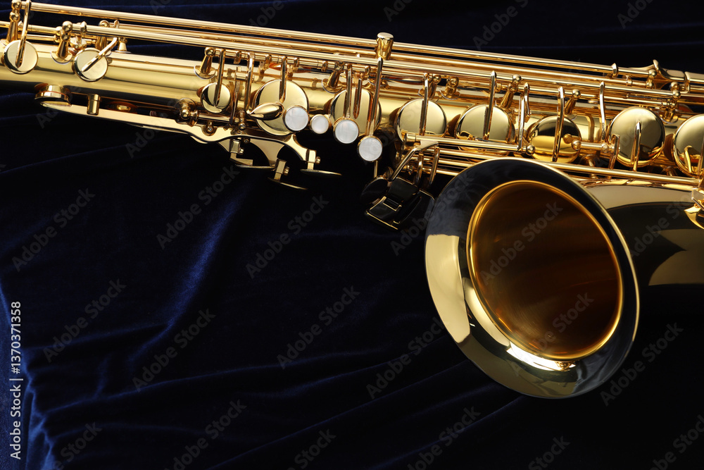 Fototapeta premium Jazz. One beautiful saxophone on dark blue fabric, closeup. Space for text