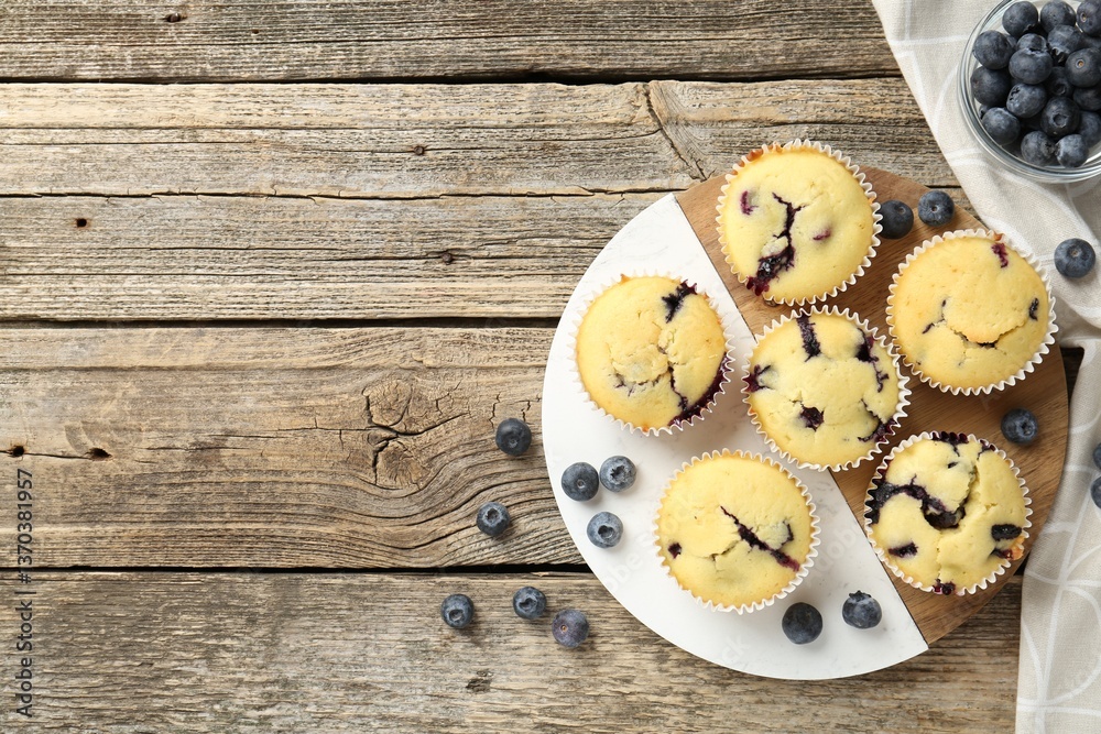 Delicious muffins with blueberries on wooden table, flat lay. Space for text Delicious muffins with blueberries on wooden table, flat lay. Space for text