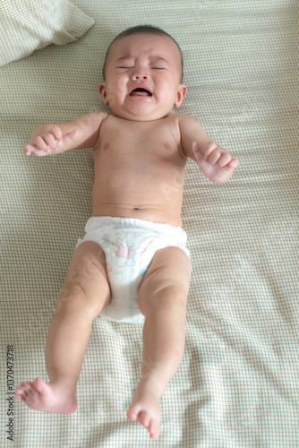 Baby crying on a bed