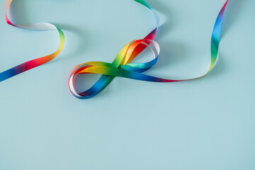 Autism acceptance month, Autism awareness day concept. Rainbow colors ribbons in shape of infinity loop on blue background. Infinity is symbol of autism disorder, adhd, neurodiversity