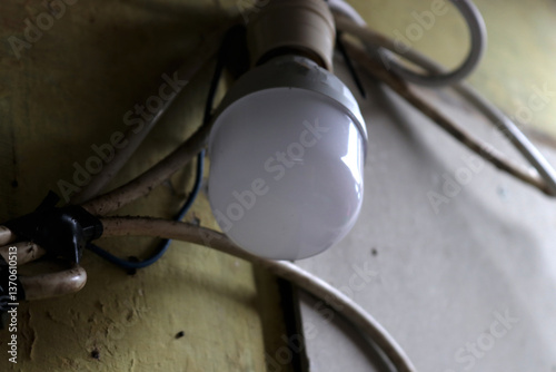 Photo of a light bulb with a cable attached to the wall of a house