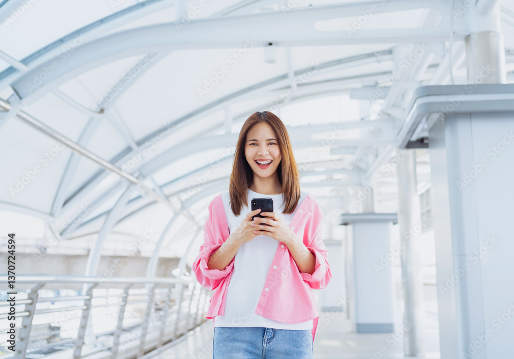 Fototapeta premium Young Asian woman using social media on smartphone in a urban city. fast connection, checking message on apps outdoors.