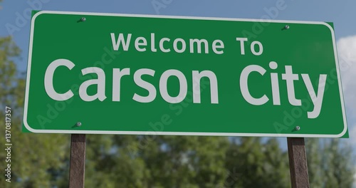 Driving By A Welcome To Carson City, Nevada Green Road Sign Against a Blue Sky and Clouds - United States Capital Series.