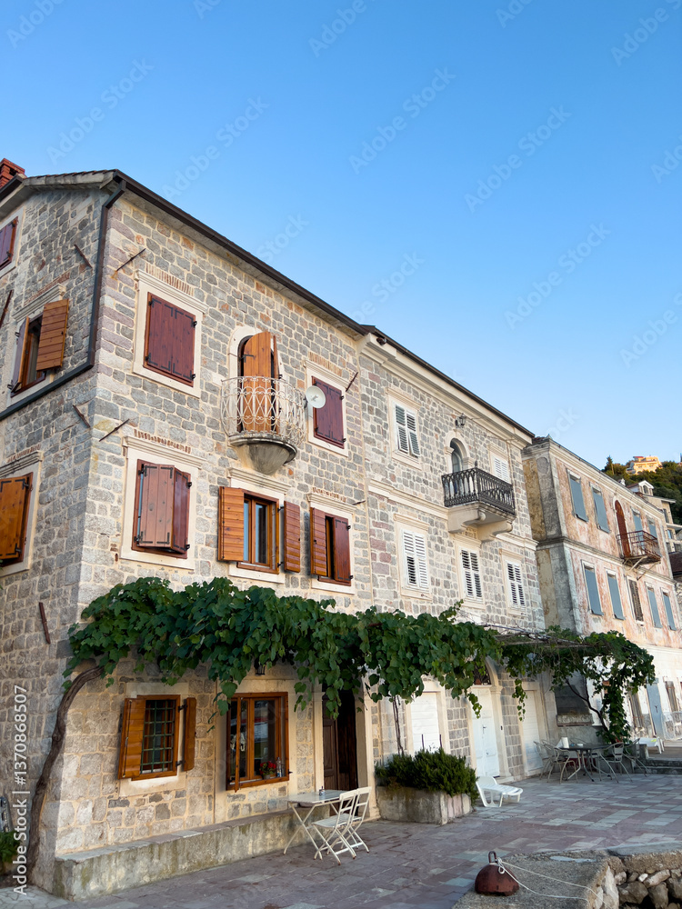 Naklejka premium Old stone building with wooden shutters on the windows and green ivy