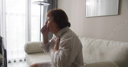 A sick person with cold symptoms, respiratory viral infection ARI , flu. Weakened immunity in older adults, cold condition. An elderly woman is coughing, covering her mouth with her hands due to a