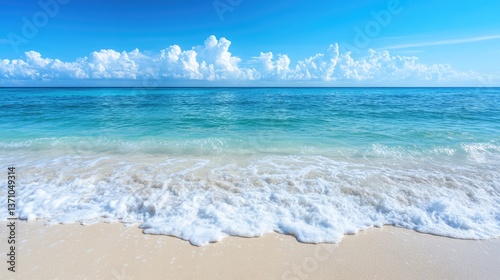 Crystal-clear turquoise ocean waves gently washing onto a pristine white sandy beach under a bright blue sky.
