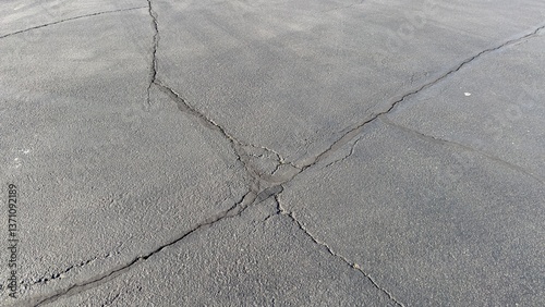 overhead view of dark gray asphalt parking surface with white painted lines cracks and worn textures empty spaces clean layout street shadows minimal urban detail captured from above
