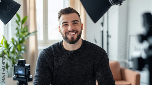 Happy young man recording a high-quality testimonial with professional lighting, natural sunlight filtering through tall windows, working comfortably in a minimalist office