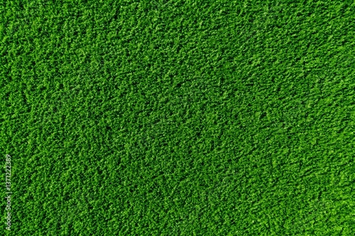 Vibrant green grass texture, lush artificial turf background, seamless lawn surface for sports field or garden landscaping, top view of dense synthetic grass carpet for outdoor design