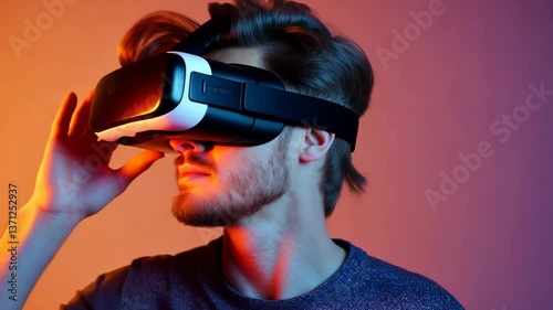 Young adult male wearing virtual reality glasses on a background illuminated with different colors. Perfect for advertisements.