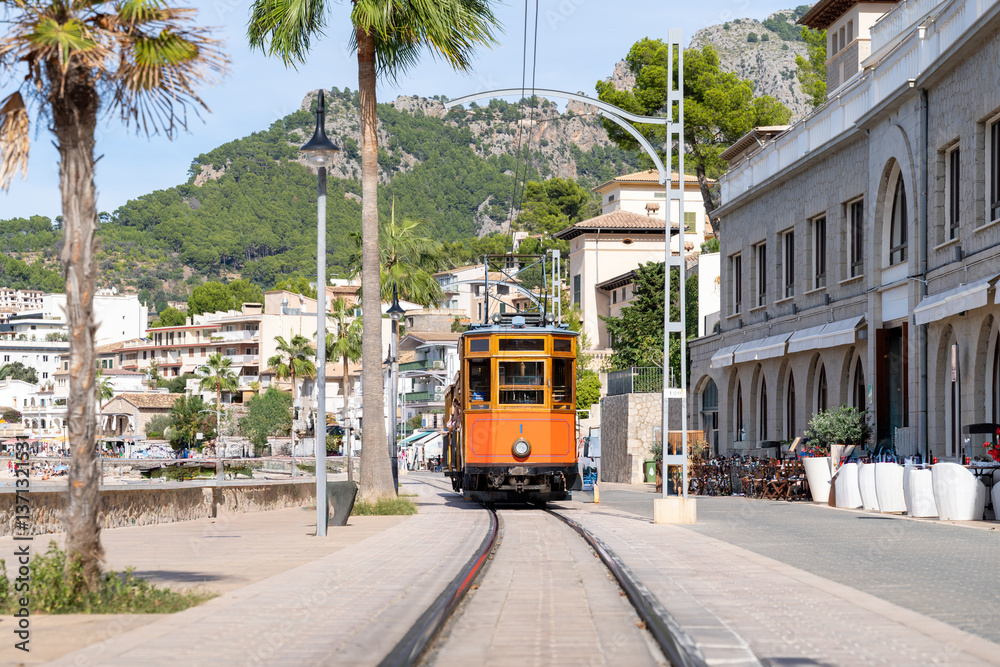 Vintage tram transports tourists through scenic Port de Soller, Majorca, Spain..