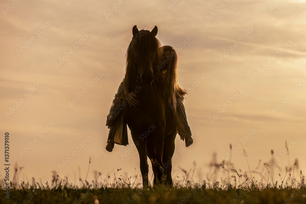 A female equestrian and her horse interacting together. Romantic freedom sunset scene