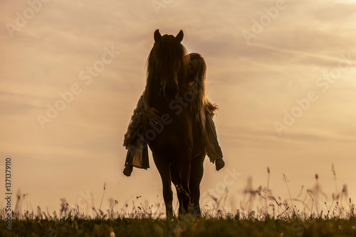 Obraz na płótnie A female equestrian and her horse interacting together. Romantic freedom sunset scene w salonie