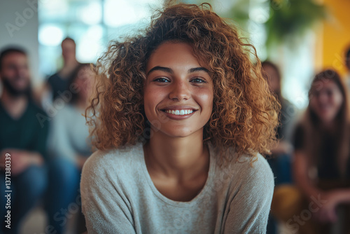 Smiling young woman with curly hair enjoying relaxed indoor conversation with friends in a warm casual setting