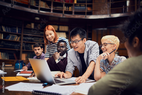 Diverse group of college students collaborating on laptop in library