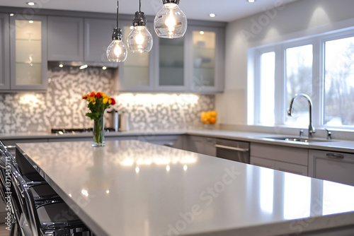 Bright Contemporary Kitchen with Polished Quartz Island Countertop and Pendant Bulb Lighting. Sleek Grey Cabinets, Glass Front Panels, and Mosaic Tile Backsplash. Natural Daylight Enhances Clean, Mode photo