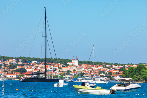 Obraz na płótnie Charm of Medulin, Croatia, with stunning coastal scene featuring luxury yachts, sailboats and picturesque town with red-roofed houses. Crystal blue waters and serene harbor create Mediterranean escape w salonie