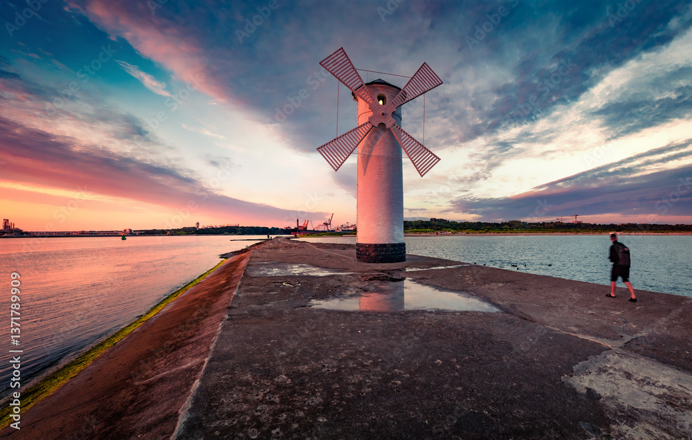 Calm summer scene of Stawa windmill. Colorful sunrise on Szczecin Lagoon. Superb morning seascape of Baltic Sea, Swinoujscie, Western Pomerania, Poland, Europe. Traveling concept background..