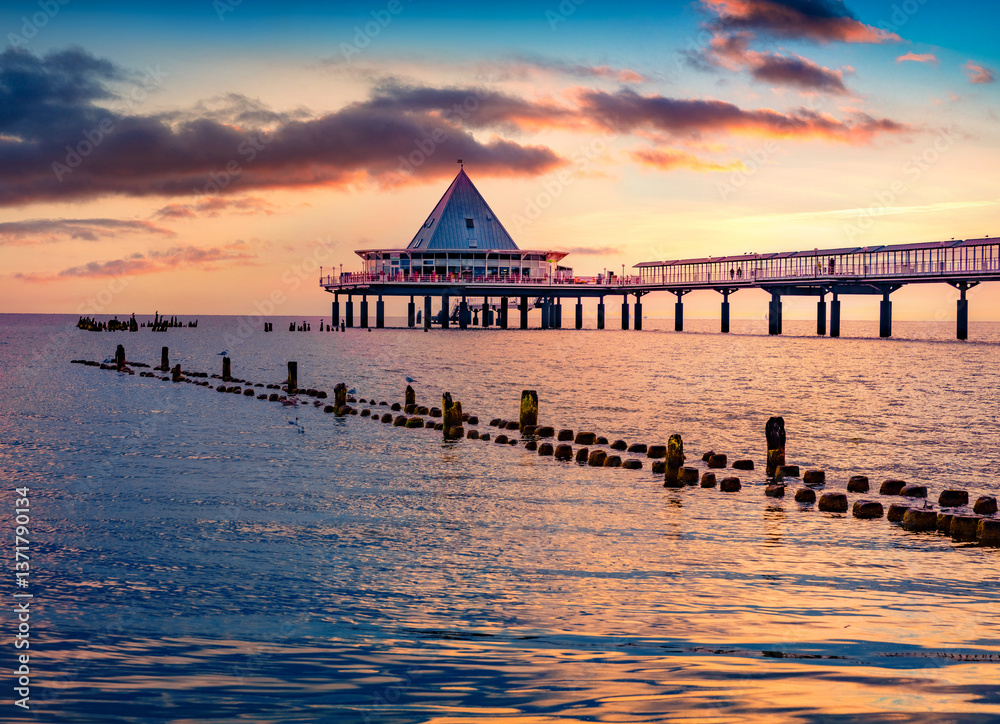 Amazing morning view of mettal boat ramp and ruins of old wooden pier. Impressive summer sunrise on popular tourist attraction - Heringsdorf Pier with a lots of Shopping mail, Germany, Europe.