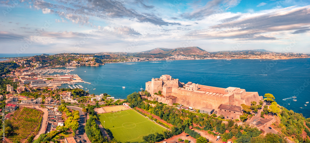 Panoramic view from flying drone of Aragonese Castle of Baia with football stadium, Italy, Europe. Captivating morning seascape of Mediterranean sea. Traveling concept background.