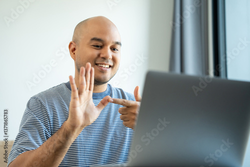 Portrait view of happy young deaf asian man showing sign language and looking at camera at home, a man with hearing disability having communication with hands gestures concept.