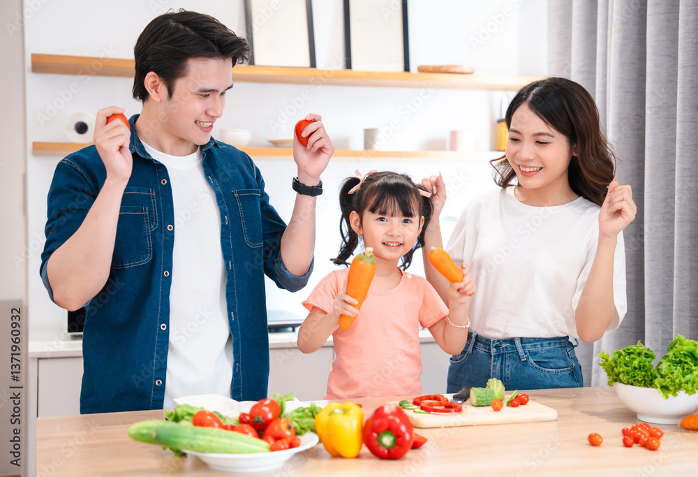 Happy family preparing a meal together in the kitchen while making playful poses with vegetables