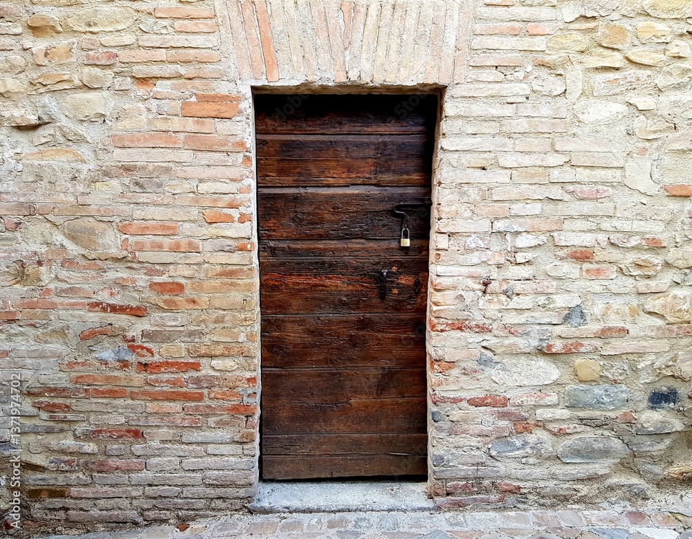 Old wooden door in a stone wall. Tuscany, Italy