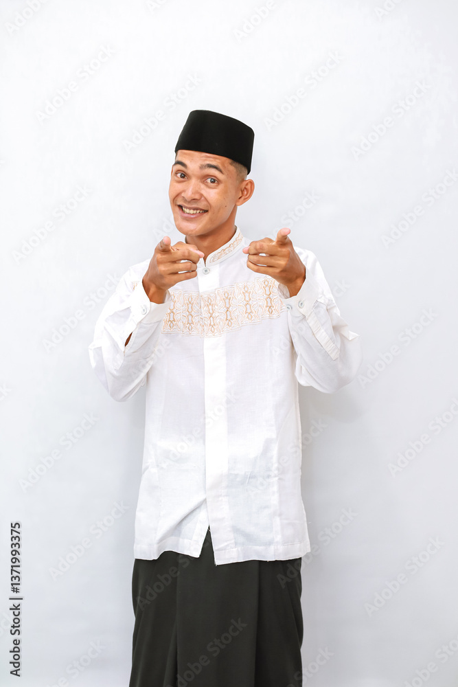 Enthusiastic Asian Muslim Man Points Forward with Cheerful Expression Enthusiastic Asian Muslim Man Points Forward with Cheerful Expression