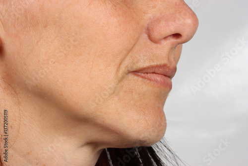 A close-up profile view of a 40-year-old Caucasian woman’s face, highlighting natural wrinkles and fine lines. The image captures the beauty of aging with soft lighting and a neutral background