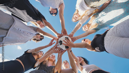 High school students demonstrating teamwork, unity, and sportsmanship by holding a soccer ball together during summer break