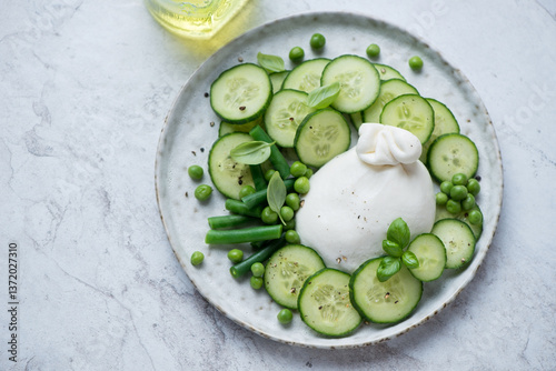 Foto Salad with burrata, fresh cucumber, green peas and basil, horizontal shot on a w