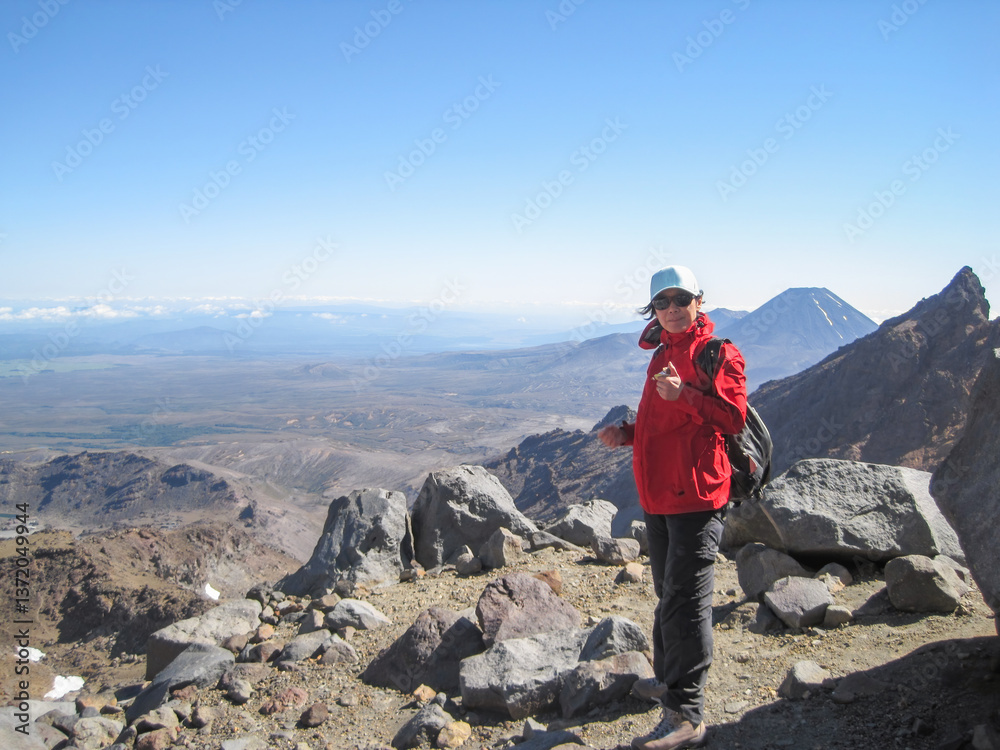 Woman hiking Mt Ruapehu summit track. Mt Ngauruhoe in the distance. North Island. New Zealand.