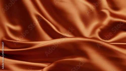 Soft orange silk fabric with gentle folds and waves creating a smooth, luxurious texture