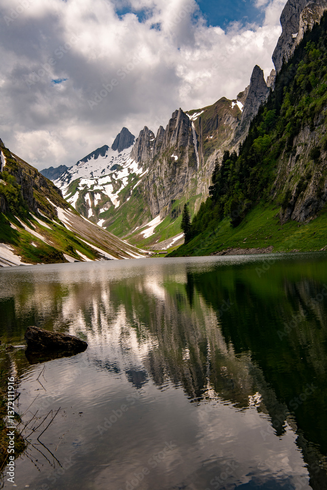 Fototapeta premium Fälensee on a spring tour in the Alpstein photographed with beautiful reflections of the mountain peaks. It is a lake in the Alpstein range of the canton of Appenzell Innerrhoden, Switzerland at 1446m
