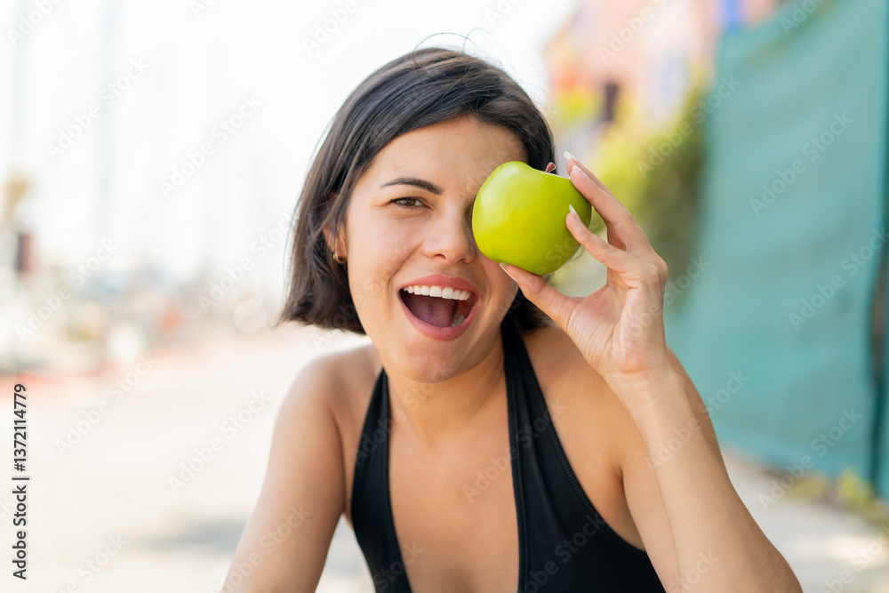 Young pretty Bulgarian woman at outdoors holding an apple with surprised expression Young pretty Bulgarian woman at outdoors holding an apple with surprised expression