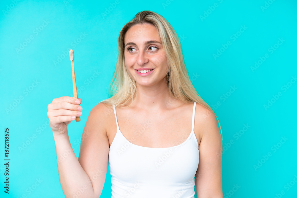 Young caucasian woman brushing teeth isolated on blue background with happy expression Young caucasian woman brushing teeth isolated on blue background with happy expression
