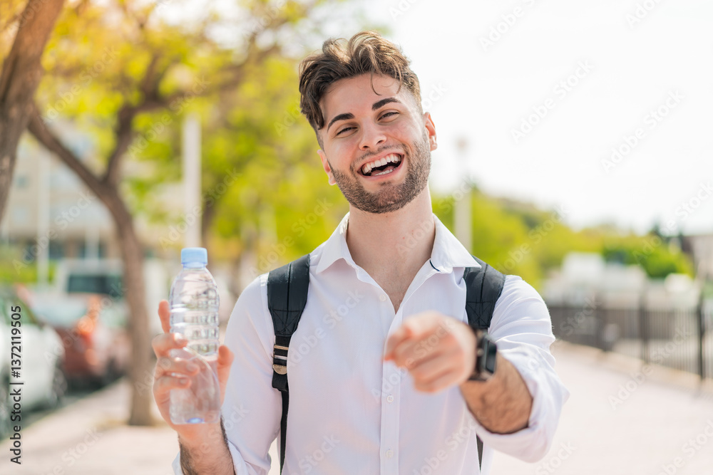 Young handsome man with a bottle of water at outdoors points finger at you with a confident expression Young handsome man with a bottle of water at outdoors points finger at you with a confident expression