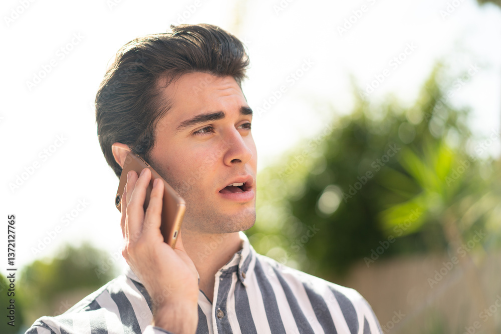 Young handsome man keeping a conversation with the mobile phone with someone