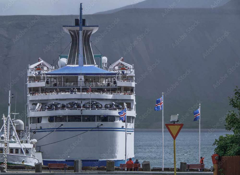 Classic expedition cruiseship cruise ship liner Delphin docked at pier in Grundafjördur, Iceland with harbor skyline and fjord landscape in background on during Arctic Circle summer cruising
