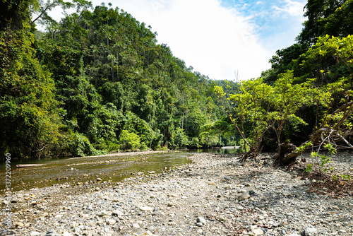 Wild river flowing through dense rainforest in the remote coastal region of Salat Rabia, Triton Bay, West Papua, Indonesia. A pristine tropical landscape of jungle and rocks.