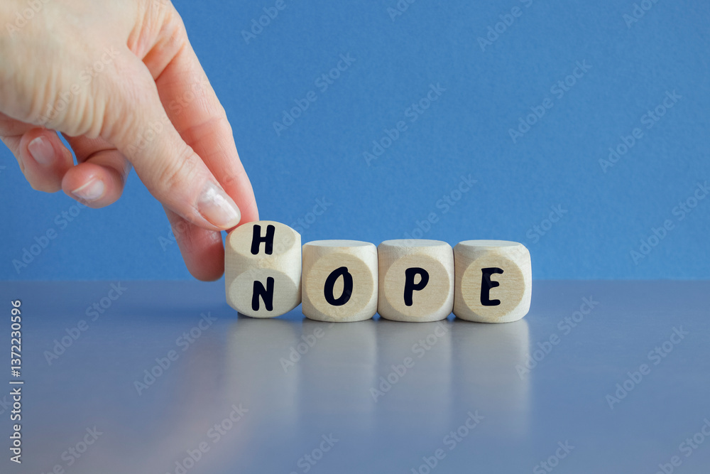 Hope or nope symbol. Male hand turns cubes and changes the word 'nope' to 'hope' on a beautiful blue background. Business and hope or nope concept.