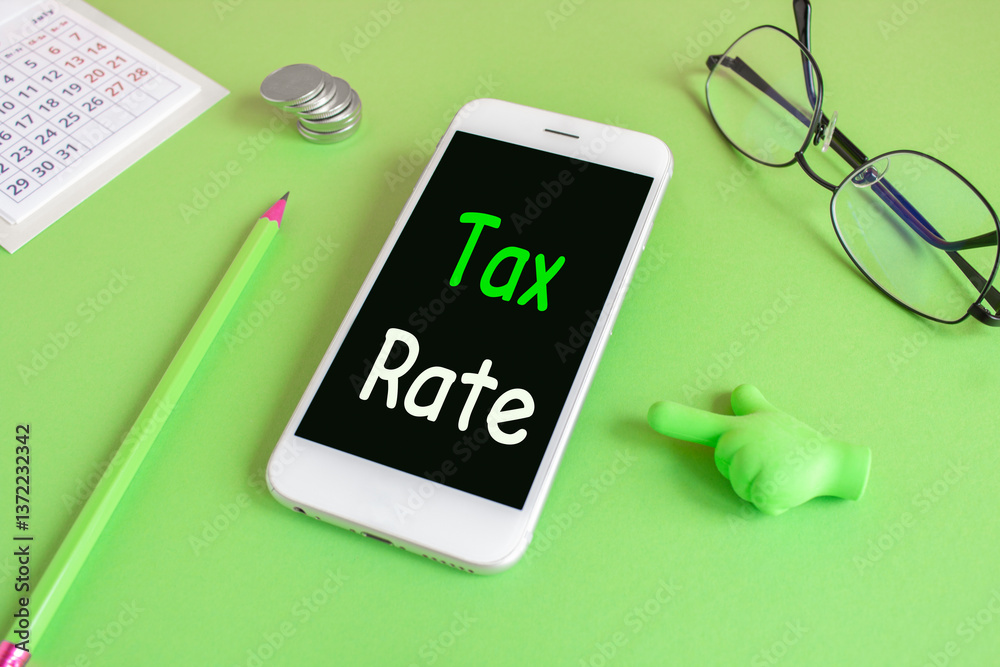 Tax rate symbol. Concept words Tax rate written on the mobile phone screen. Beautiful green background. Glasses, coins. Business concept.