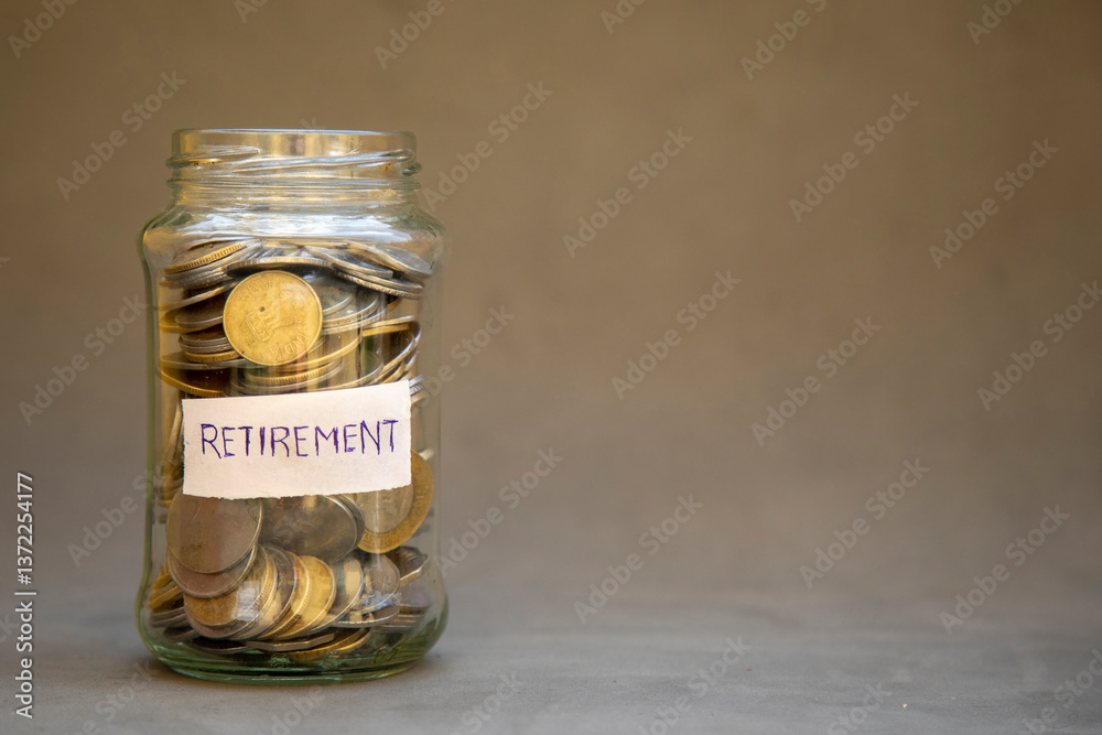 A close-up of a glass jar filled with coins and labeled 'Retirement'. Emphasizing concepts of savings, financial security, and planning for the future. Neutral background for versatile thematic use. A close-up of a glass jar filled with coins and labeled 'Retirement'. Emphasizing concepts of savings, financial security, and planning for the future. Neutral background for versatile thematic use.