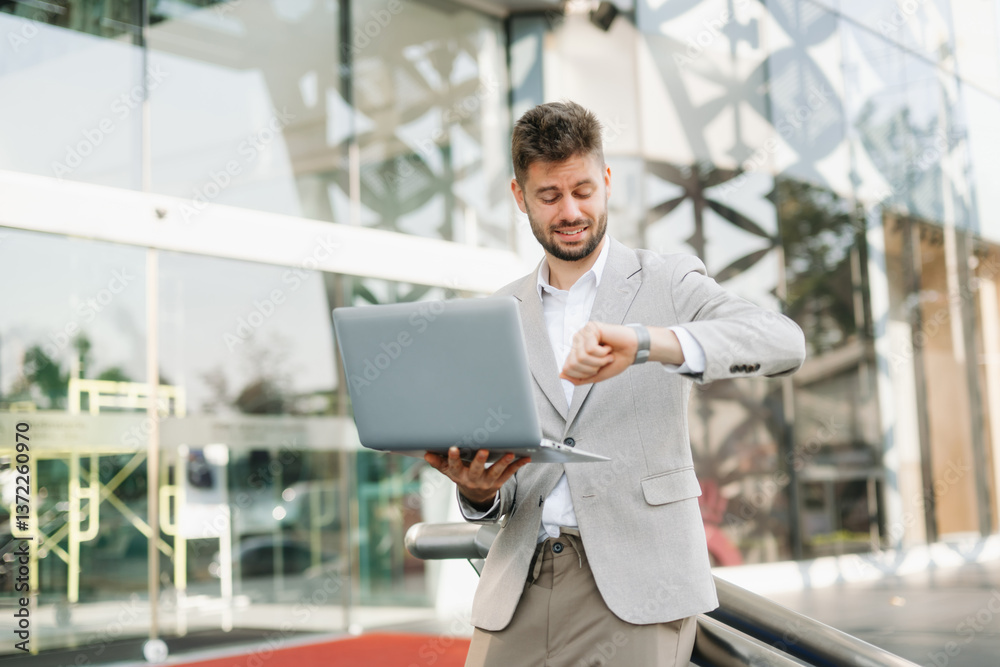 Fototapeta premium Successful businessman works outdoors near the office holds a tablet