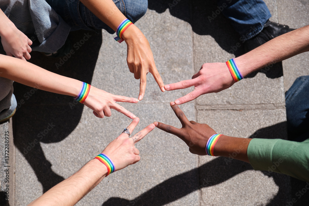 Group of activists wearing rainbow bracelets forming star shape with their fingers