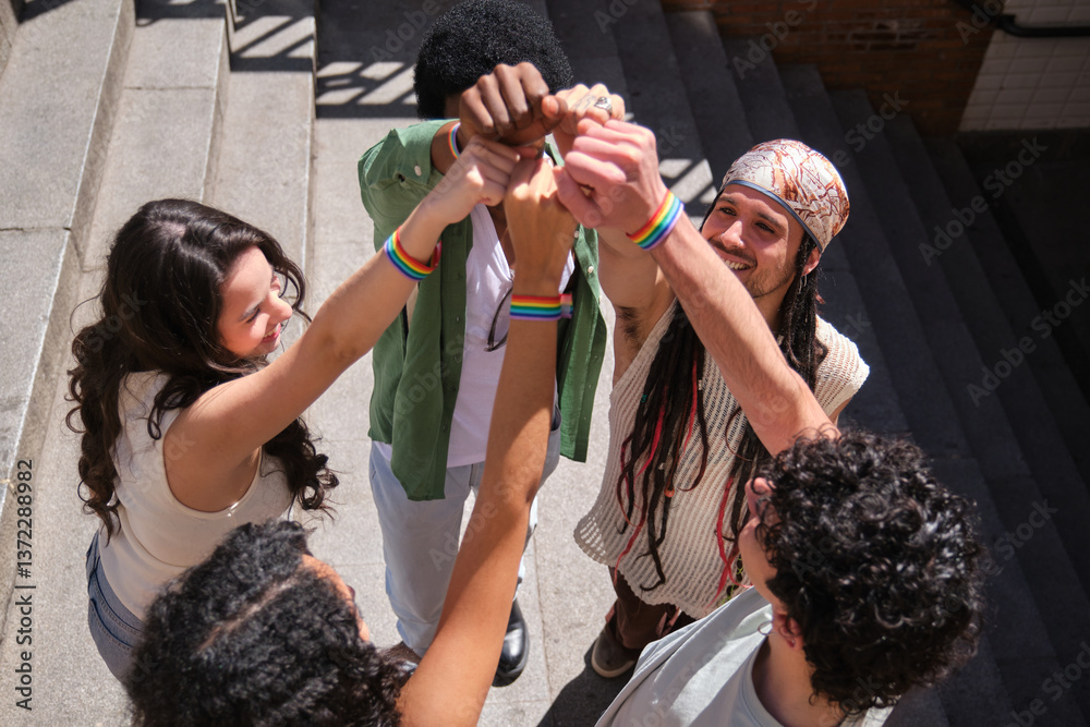 Happy multi ethnic activists joining hands and showing rainbow bracelets on wrists, fighting for lgbtq plus rights and equality