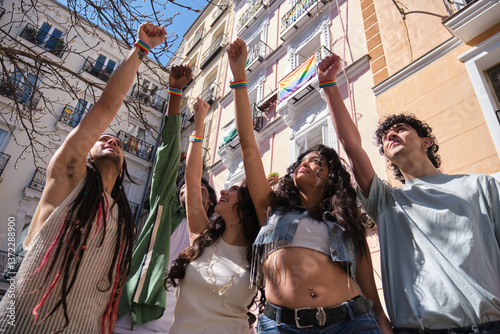 Obraz na płótnie Group of young activists raising fists wearing rainbow wristbands at a LGBT pride parade in the city w salonie