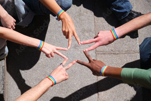 Obraz na płótnie Group of activists wearing rainbow bracelets forming star shape with their fingers w salonie